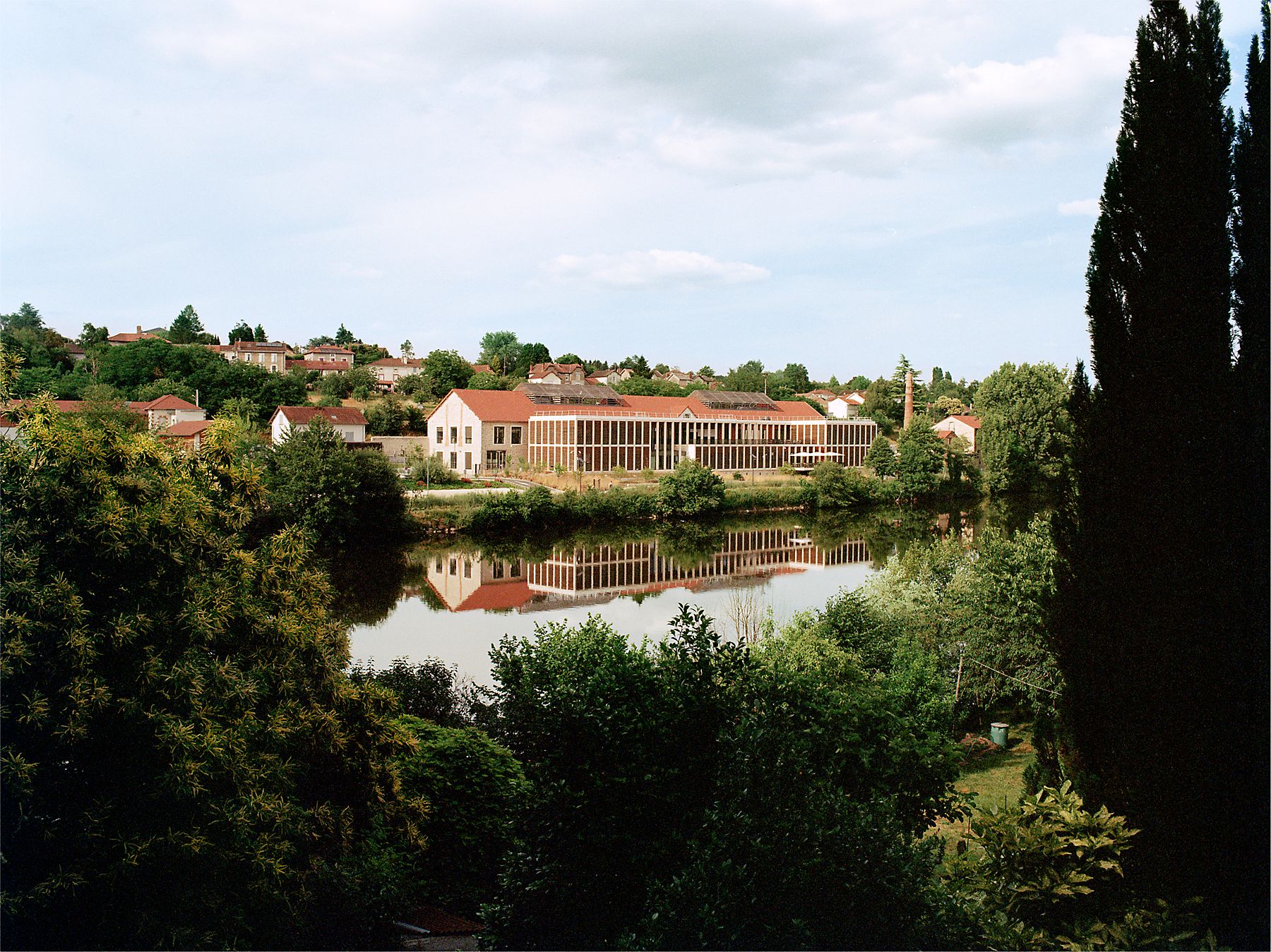An Hermès production site surrounded by trees and reflected in water